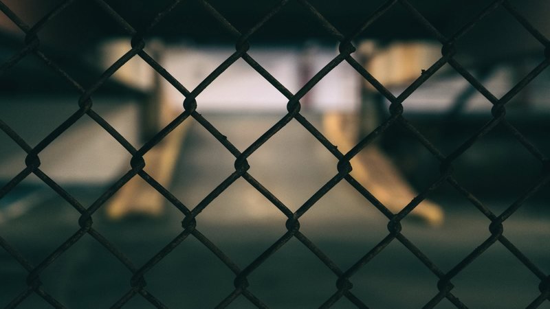 Tight view of chain-link fabric with warm light behind it.